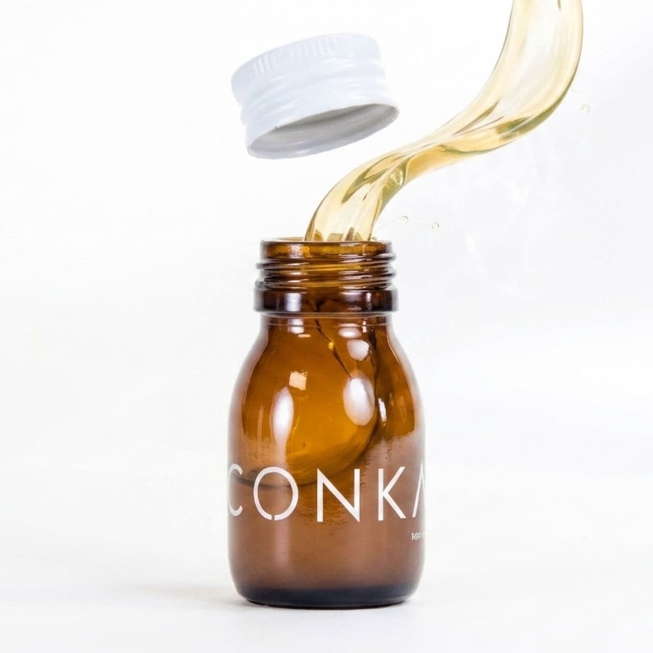 CONKA liquid pouring from an amber bottle