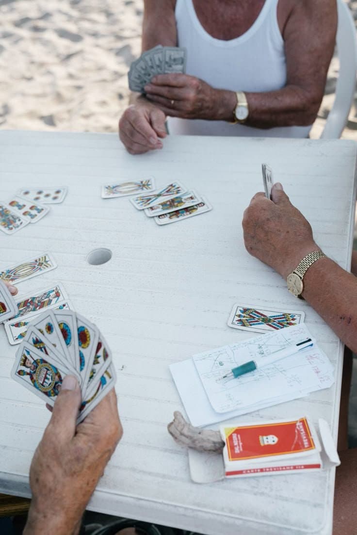 Four friends playing cards at an outdoor table